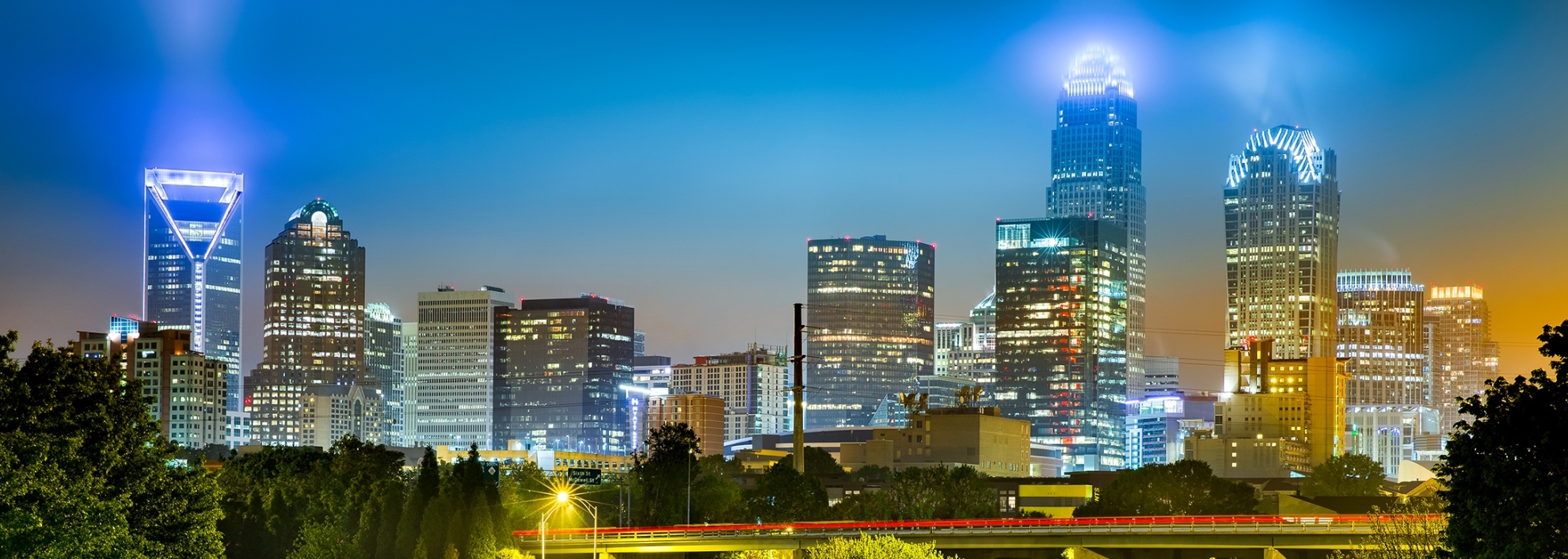 Traffic light trails in Charlotte, North Carolina. The city skyline glows on a foggy night.